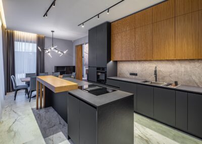 Modern kitchen with sleek black cabinetry, wooden accents, and integrated appliances, adjacent to a dining area with a minimalist table and chair setting.